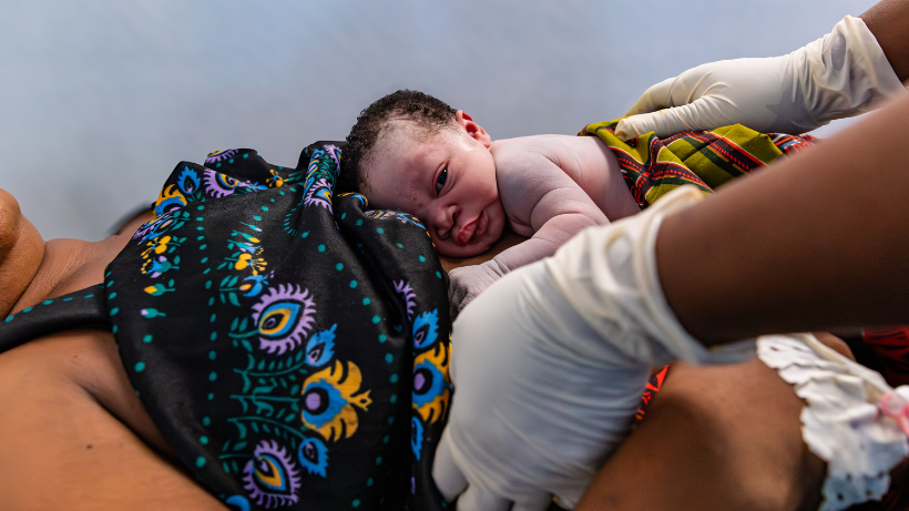 Togo, 2025. „2 Hours to Life“ – eine Partnerschaft zwischen UNFPA und Takeda im Bereich der geburtshilflichen Notfallversorgung. Ein Neugeborenes wird unmittelbar nach der Geburt auf die Brust der Mutter gelegt, wodurch ein sofortiger Hautkontakt entsteht, der die Atmung, die Wärmezufuhr und die frühzeitige Bindung fördert. Hebammen leisten in den ersten Lebensminuten auf der Entbindungsstation in Lomé Hilfe.
